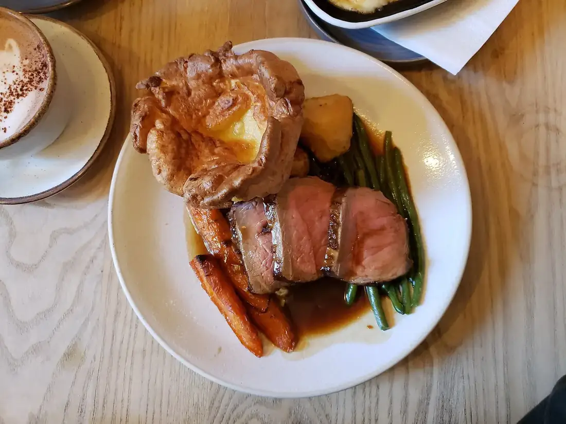 Tranches de bœuf rôti avec carottes, haricots verts, sauce et pomme de terre sur une assiette blanche