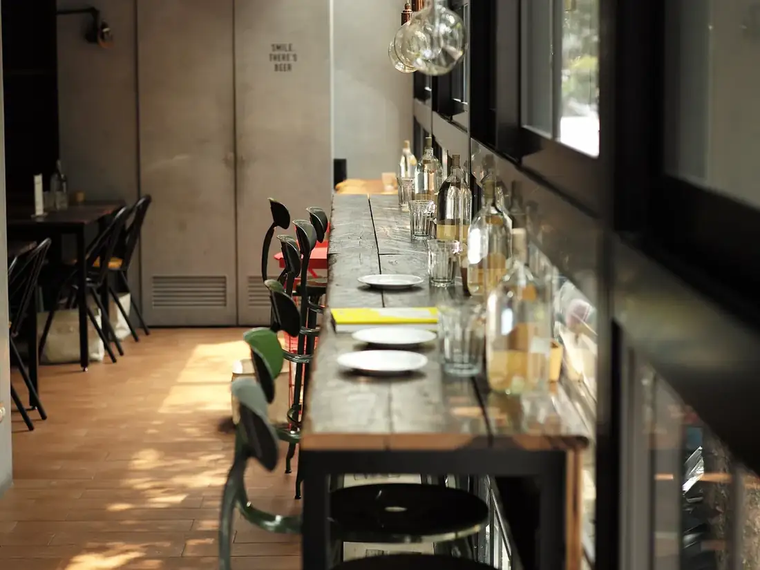 Salle de restaurant étroite avec une longue table dressée le long d'une grande baie vitrée